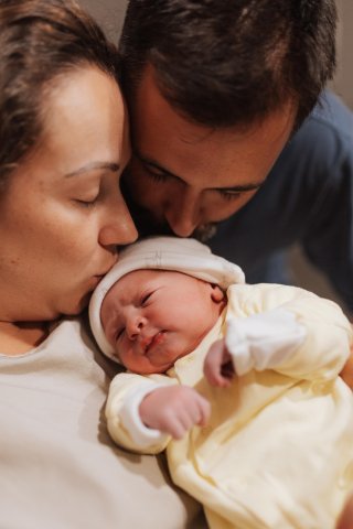 Любящая пара с нежностью обнимает своего новорожденного ребенка дома в уютной обстановке в вечерние часы